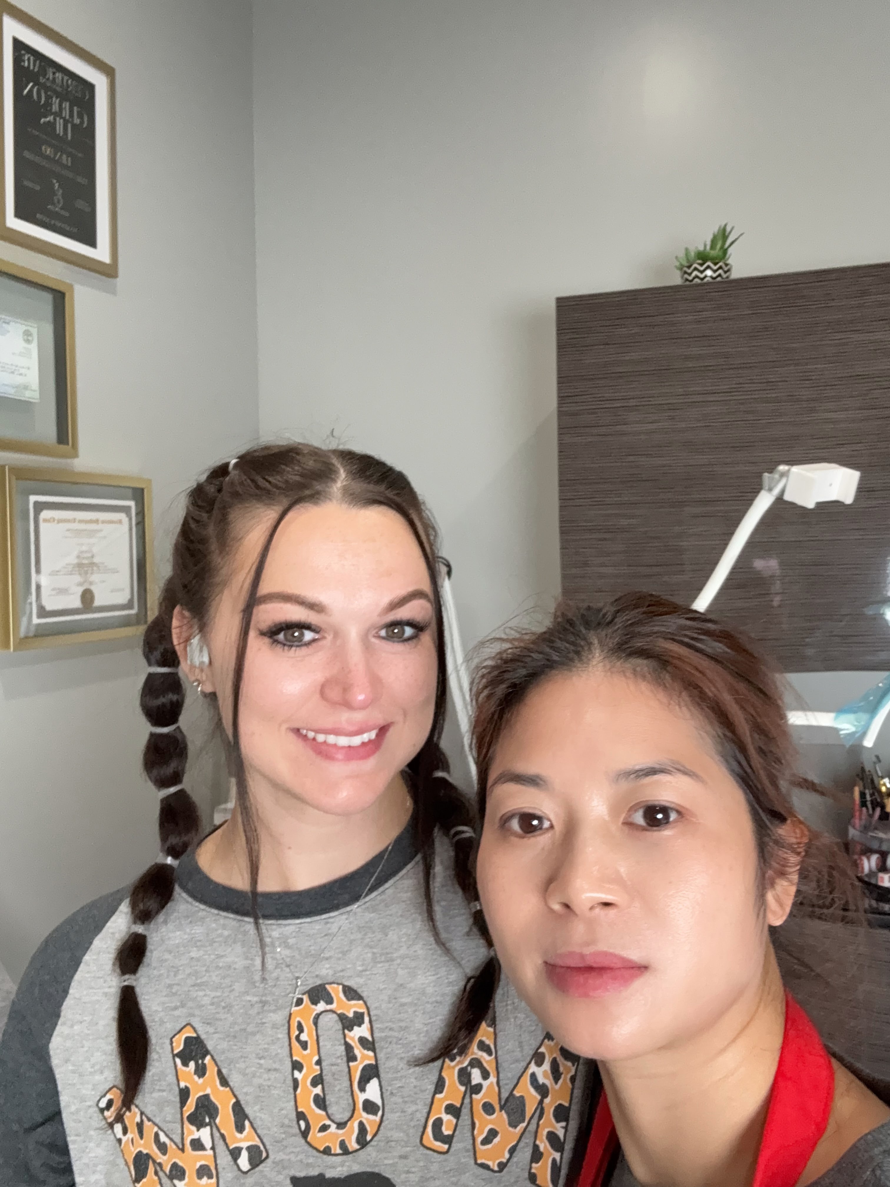 Client selfie with Lynn Do in front of IrisBrows accent wall